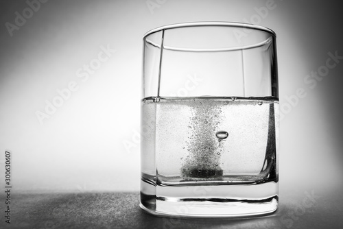 Effervescent aspirin tablet dropping to glass of water photo