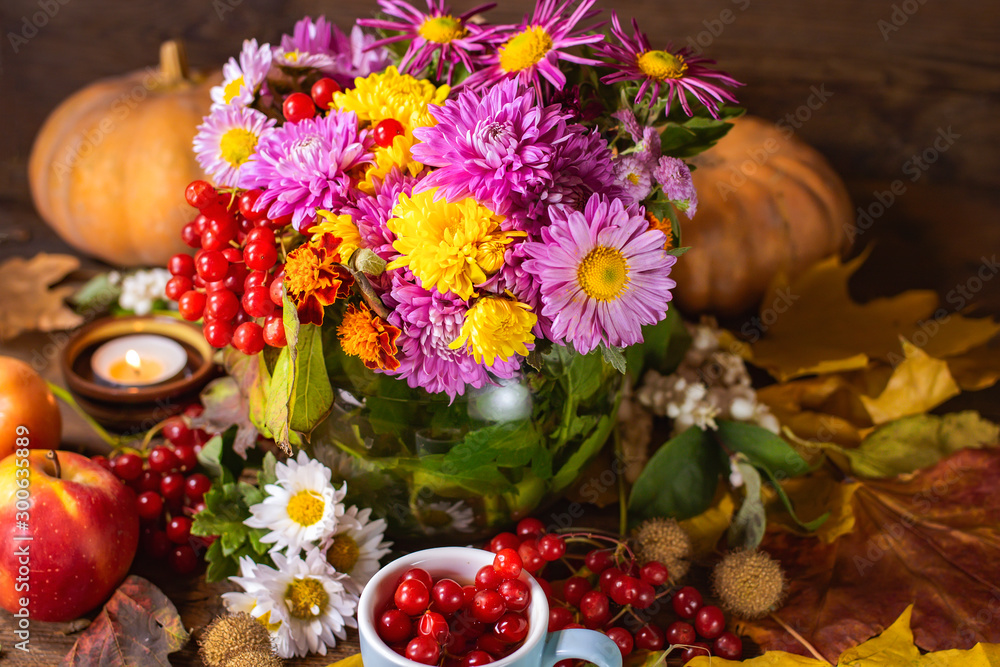 Fototapeta premium multi-colored autumn chrysanthemums and a cup of tea with mountain ash.