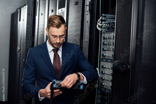 bearded businessman holding reflectometer in server room photo