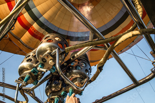 Closeup of the inside of a hot air balloon and a hand operating the flamethrower with flames. Travel, air, transport, aviation, trip, adventure, summer concept.