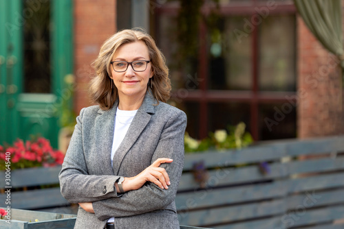 Portrait of a pretty mature business woman 55 years old, outdoors in the city.