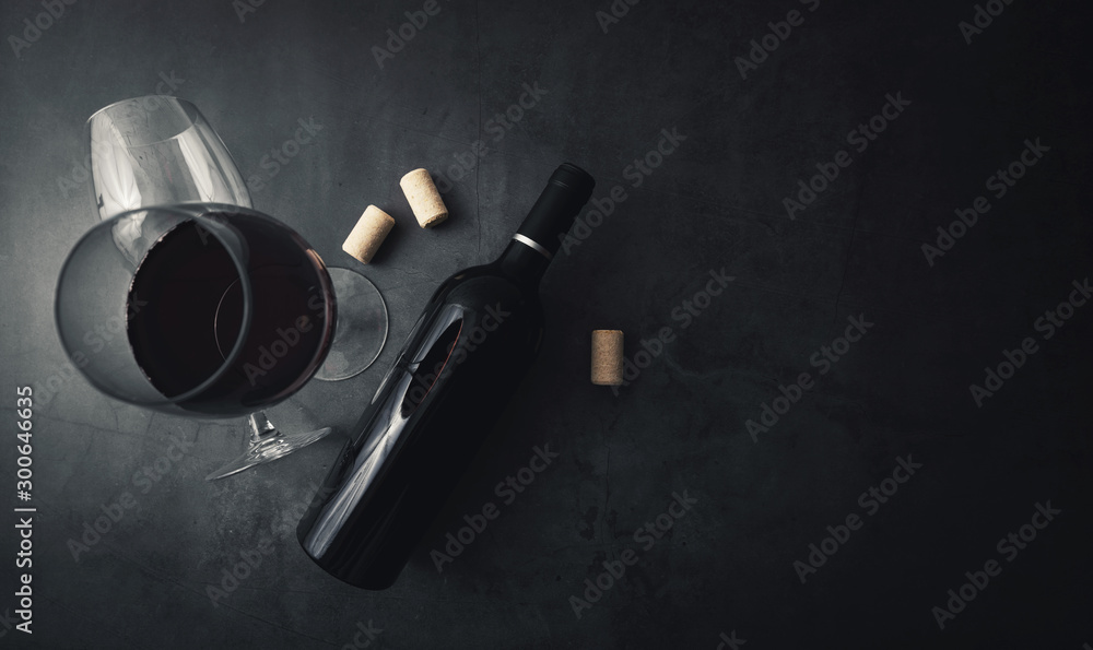 red wine bottle and glass on black stone background with copy space