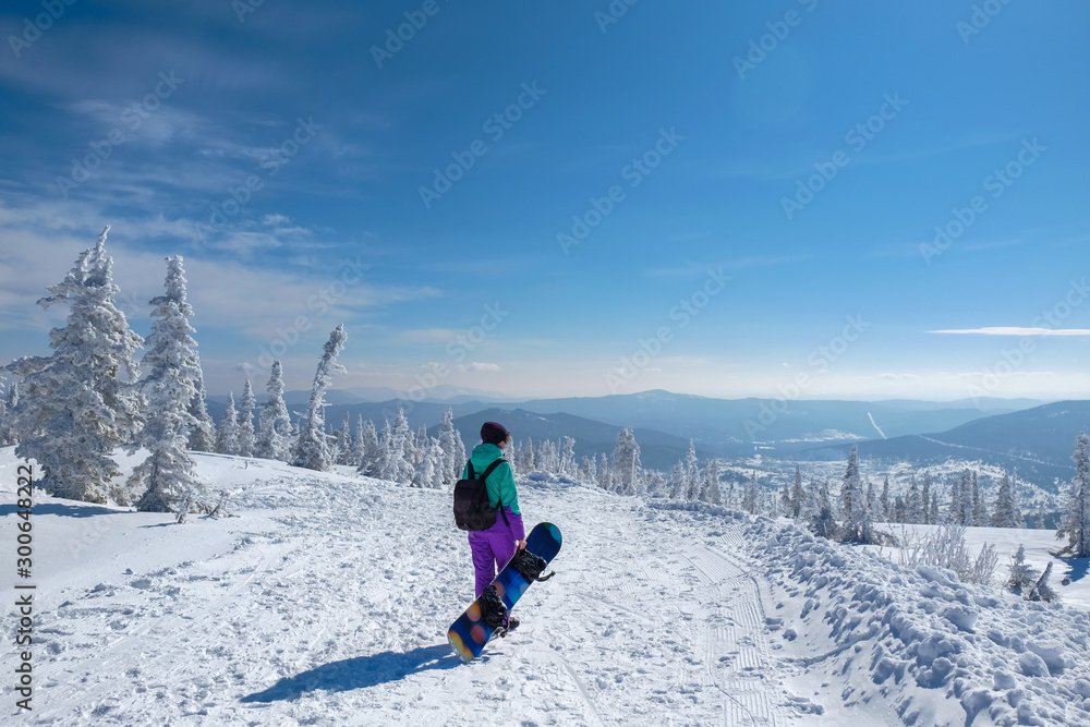 Young snowboarder in the mountains on top. Active rest on a snowboard.