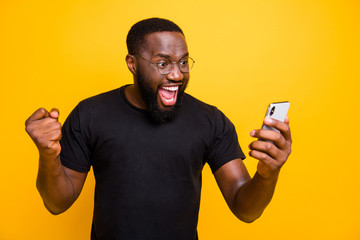 Photo of overjoyed crazy casual brown haired bearded man in eye glasses t-shirt rejoicing in victorious event expressing emotions on face isolated vivid color yellow background