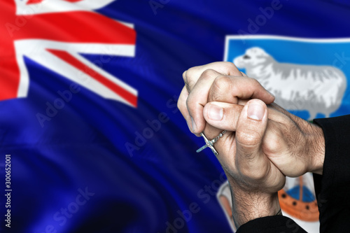 Falkland Islands flag and praying patriot man with crossed hands. Holding cross, hoping and wishing.