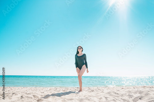 Girl with black hair is walking along the beach in a bodysuit