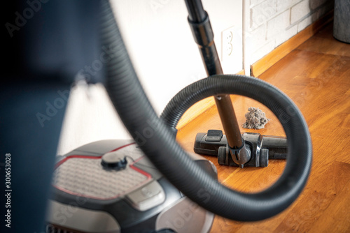 Vacuum cleaner and dust particles on the wooden floor. Household and cleaning concept.