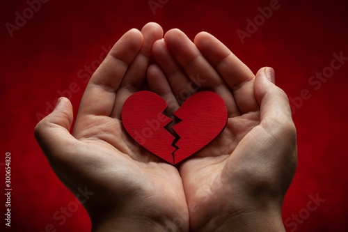 Woman holds broken heart in her hands. Crack in the red heart, Breaking the relationship photo