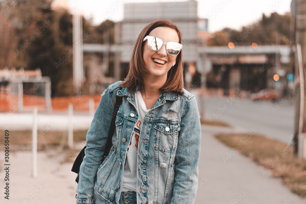 Fototapeta premium Fashionable girl laughing to camera while resting in summer day