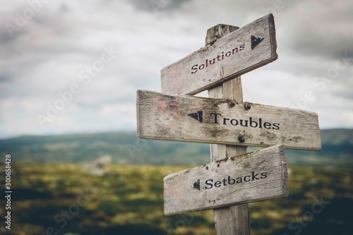 Solutions, troubles and setbacks text on wooden signpost outdoors in nature. Business, corporate, leadership concept. photo