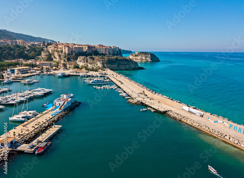 Aerial view of boats moored at the Port of Tropea, Calabria, Italy. Houses overlooking the sea. Beach and Sanctuary on the horizon. Italian coasts © Naeblys