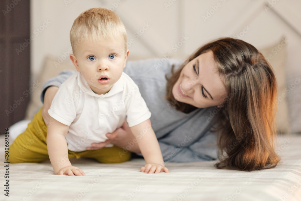 mother teaches the baby to crawl, happy mother and son on the bed mother teaches the baby to crawl, happy mother and son on the bed