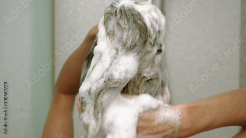 Young attractive woman taking a shower in bathroom. Beautiful girl washing her body under a shower. Slow motion. HD