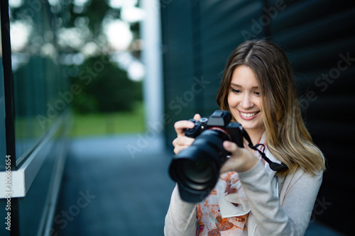 Attractive happy young freelancer woman talking pictures outdoors