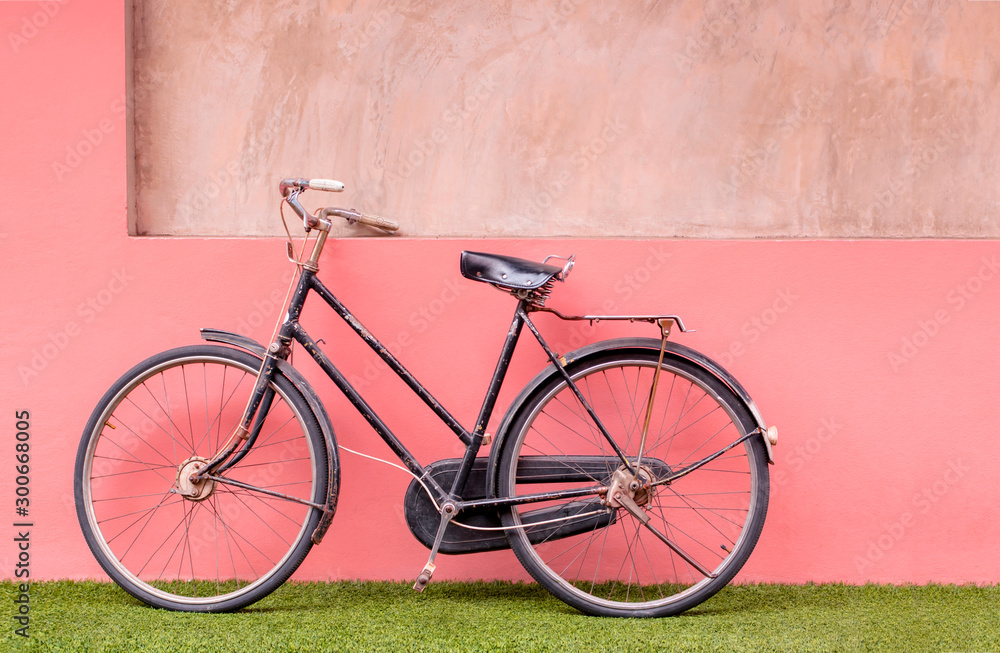 Vintage bicycle on lawn and pastel concrete wall background