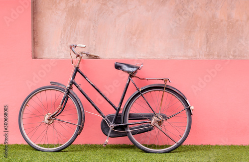 Vintage bicycle on lawn and pastel concrete wall background