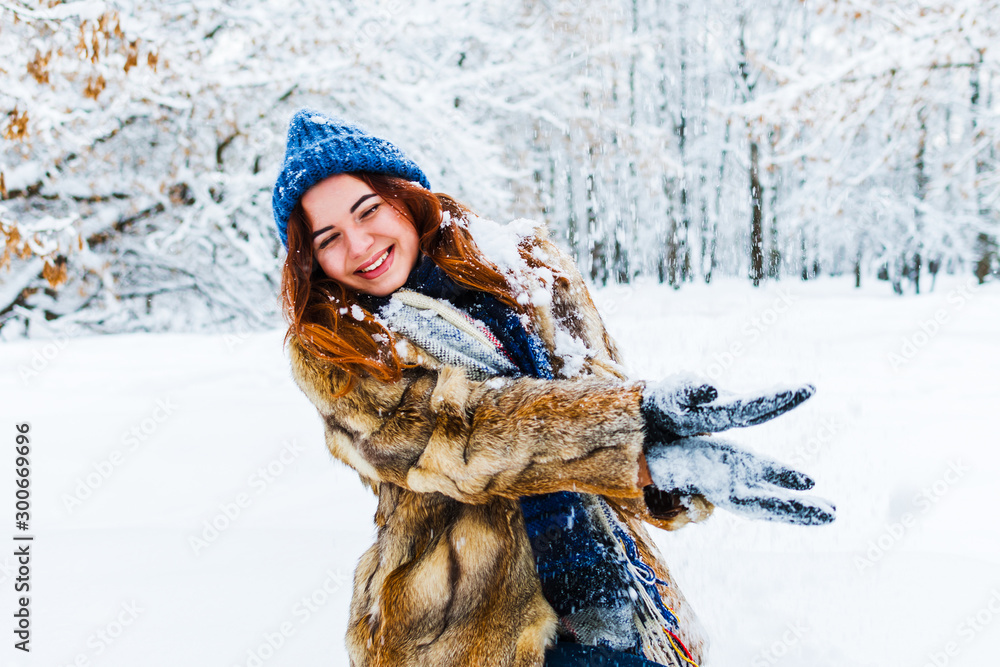 young beautiful woman playing with snow in winter forest