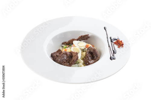 Russian traditional salad Olivier with beef and egg on top isolated on white background