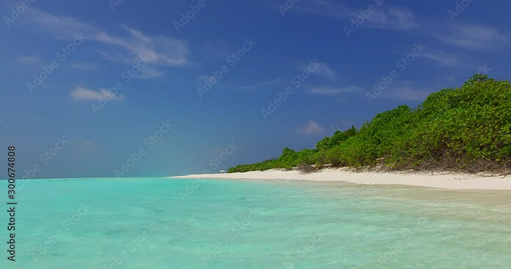 Calm ocean surface and the idyllic tropical island sandy beach with lush vegetation towering into the clear blue sky of Fiji Calm ocean surface and the idyllic tropical island sandy beach with lush vegetation towering into the clear blue sky of Fiji