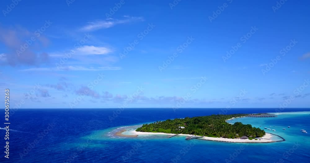 Light blue sky and navy blue ocean surrounding stunning tropical island with tourist resorts in Caribbean Light blue sky and navy blue ocean surrounding stunning tropical island with tourist resorts in Caribbean