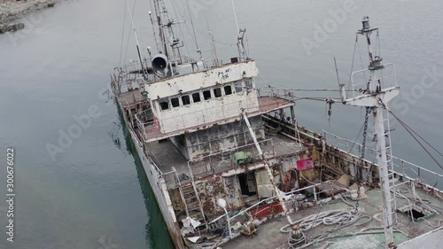 Rusty grey half submerged shipwreck anchored near the shore on a cloudy overcast day. Slow aerial dolly shot. photo