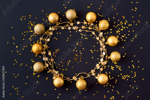 Flat lay frame with gold christmas balls and golden confetti on a dark background