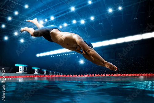 Canvas Print Swimmer jumping from starting block in a swimming pool