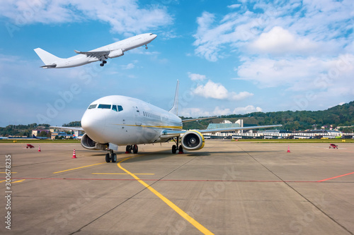 View of the airport, aircraft parked and taking off plane above the terminal building.