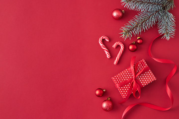 Flat lay border with branches spruce,christmas red balls and gift box on a red background
