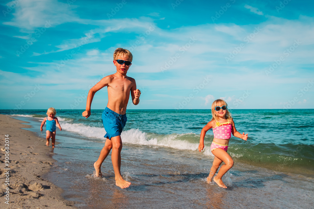 happy kids -little boy and girls- run play at beach