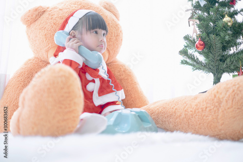 Merry christmas happy little child in santa red hat with Big teddy bear holidays in home  christmas concept