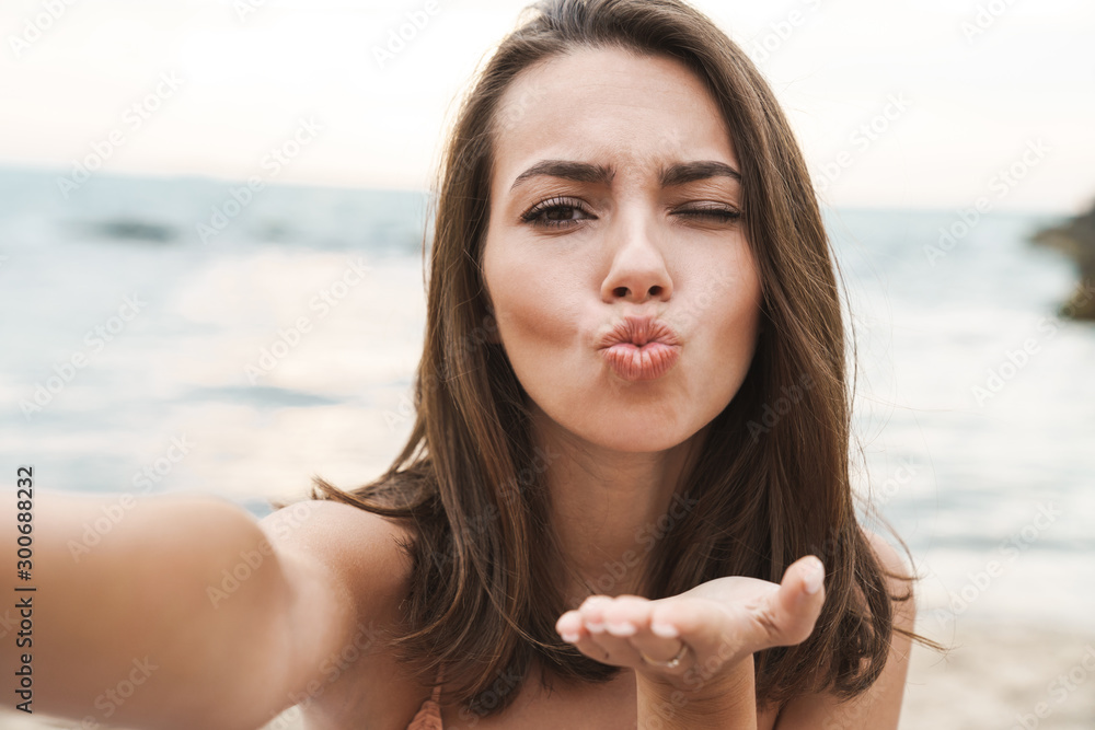 Image of nice woman sending air kiss and taking selfie photo - obrazy, fototapety, plakaty 