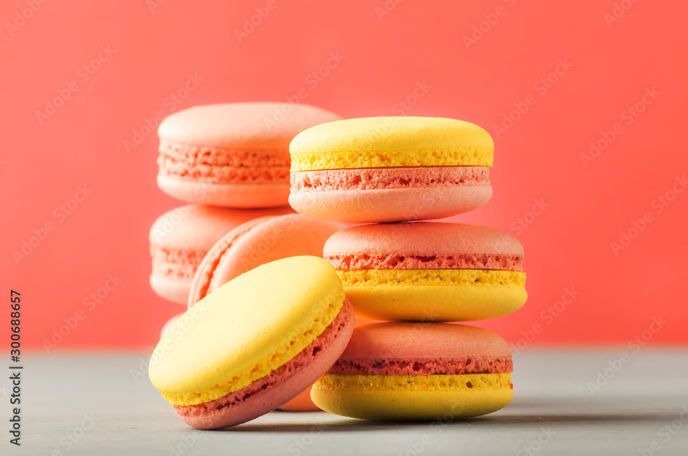Fototapeta premium Pink yellow macaroons on soft pink background table, place for text, minimalism style