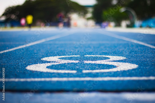 Number eight on the start of a running track .Blue treadmill with different numbers and white lines.Selective focus on Number. Blured background. Close up photo