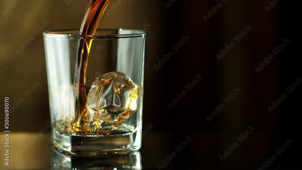 Super Slow Motion Macro Shot of Pouring Whiskey into Glass with Ice Cubes at 1000fps. Super Slow Motion Macro Shot of Pouring Whiskey into Glass with Ice Cubes at 1000fps.