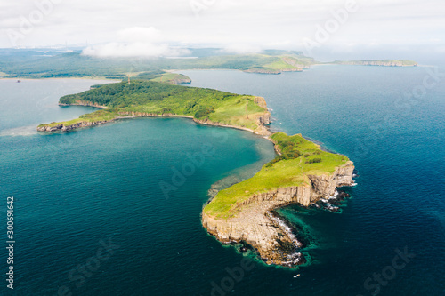 Aerial view of Cape Tobizina, Russky Island near Vladivostok. Green forest at blue sea coast, rocky and steep cliffs, sunny summer day. Seaside nature landscape in Primorsky Krai, Far East, Russia