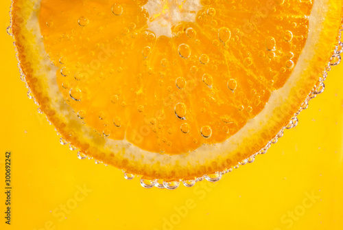 Orange and bubbling water on yellow background. Healthy, still life, summer, drinks concepts.