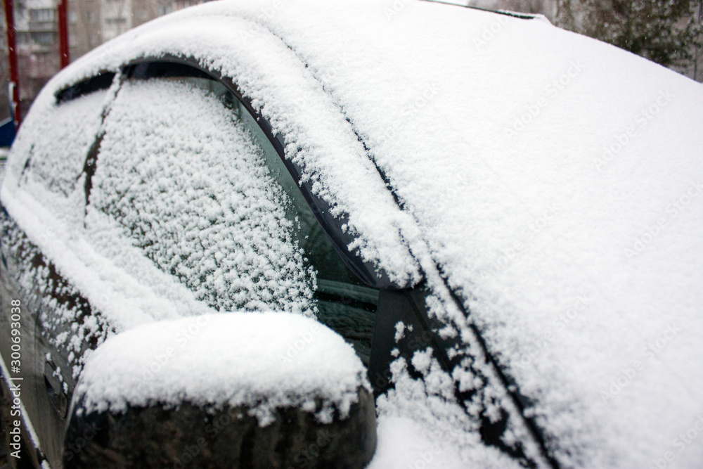 The car is covered with white fluffy snow. Winter
