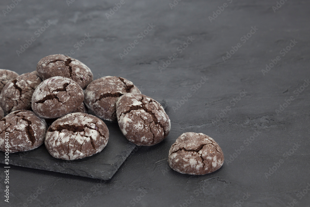Chocolate crinkle cookies on dark slate plate, gray concrete background. Christmas, recipe concept. Close-up, copy space Chocolate crinkle cookies on dark slate plate, gray concrete background. Christmas, recipe concept. Close-up, copy space