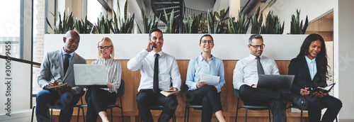 Diverse businesspeople smiling while waiting together in an offi