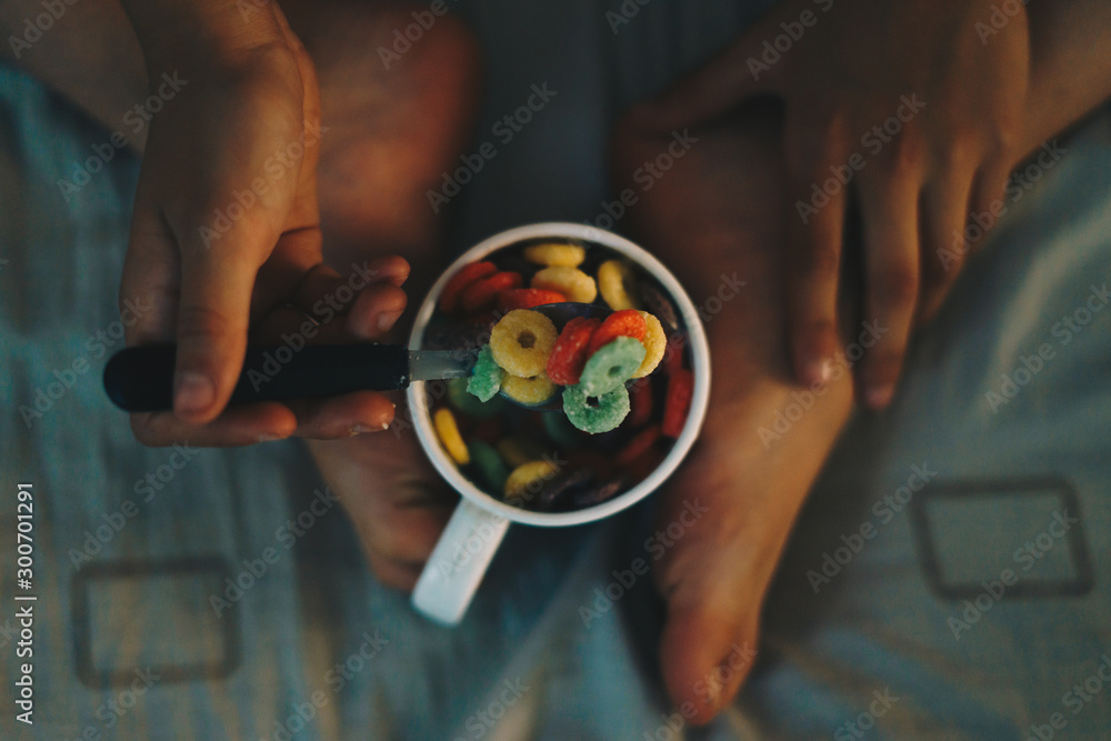 Obraz premium Young child having breakfast and eating colorful cereals in bed.