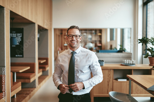 Smiling mature businessman standing alone in an office cafeteria