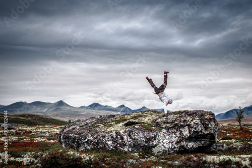 Fototapeta Man doing handstand in mountain scenery.