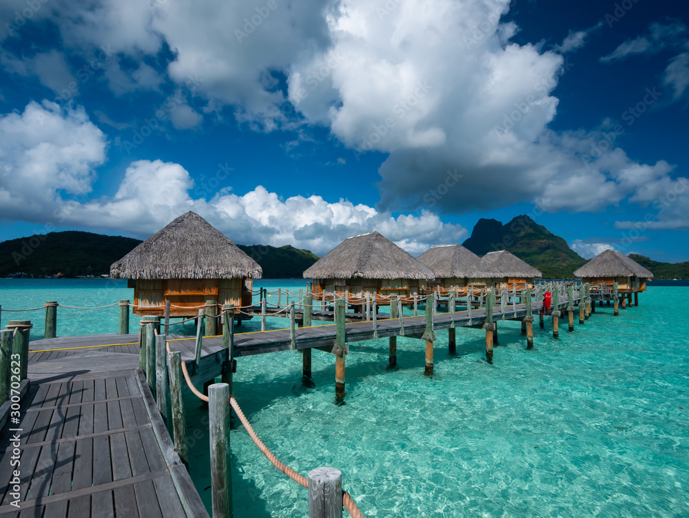 Luxury overwater villas on blue lagoon, white sandy beach and Otemanu mountain at Bora Bora island, Tahiti, French Polynesia.