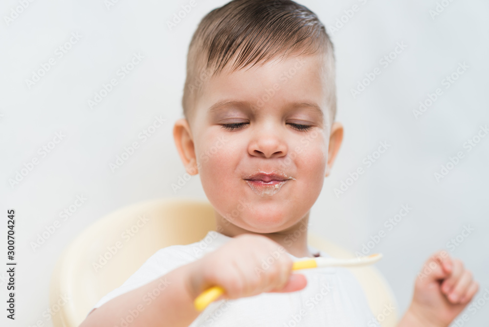 adorable baby boy eats porridge with a small spoon himself adorable baby boy eats porridge with a small spoon himself