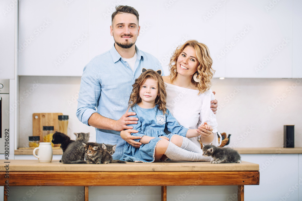 Family father, mother and sweet daughter happy together with little fluffy kittens in the kitchen in a bright home interior Family father, mother and sweet daughter happy together with little fluffy kittens in the kitchen in a bright home interior