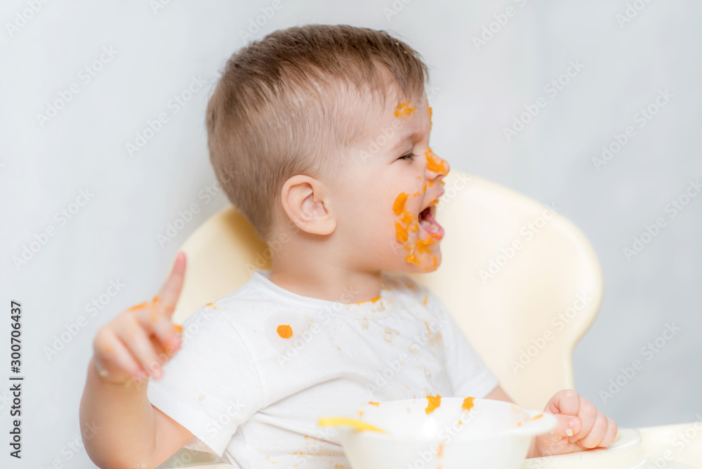 cute baby boy while eating smeared his face with a pumpkin cute baby boy while eating smeared his face with a pumpkin