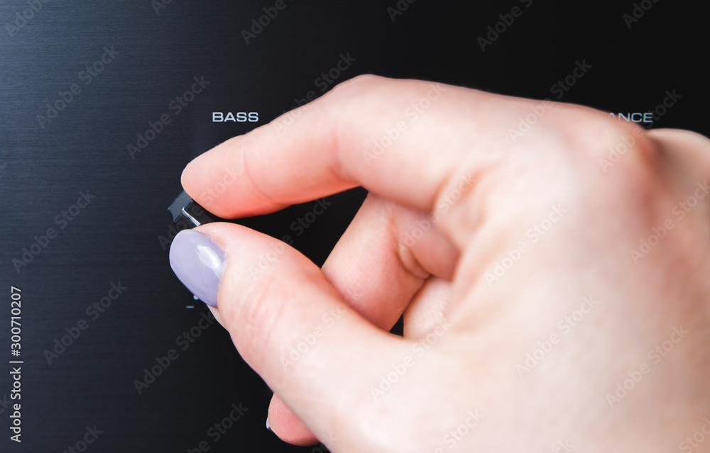 Man's hand adjiusting volume knob of subwoofer audio amplifier,volume control music concept Man's hand adjiusting volume knob of subwoofer audio amplifier,volume control music concept