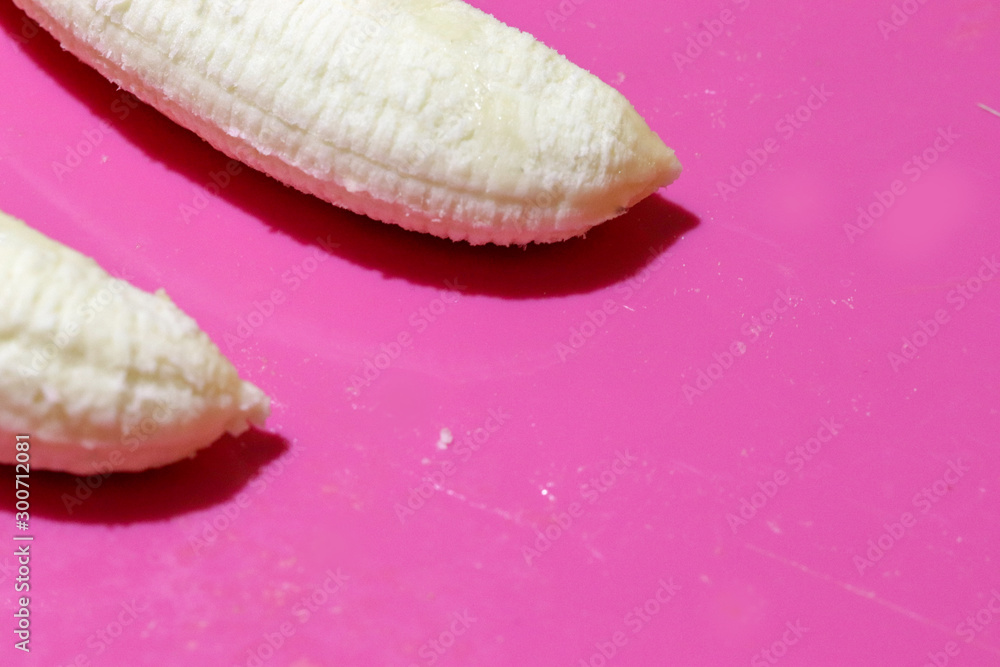 Two fully peeled bananas on a pink background top view close-up. Flat lay with copy space for text