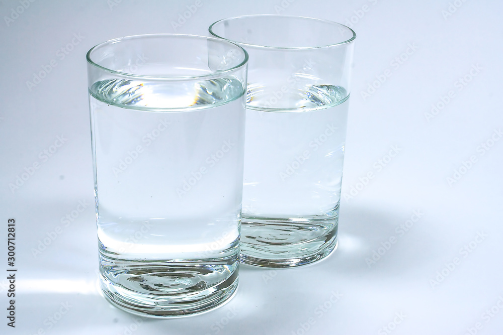 Two transparent glasses filled with clean water on a white background. Two transparent glasses filled with clean water on a white background.